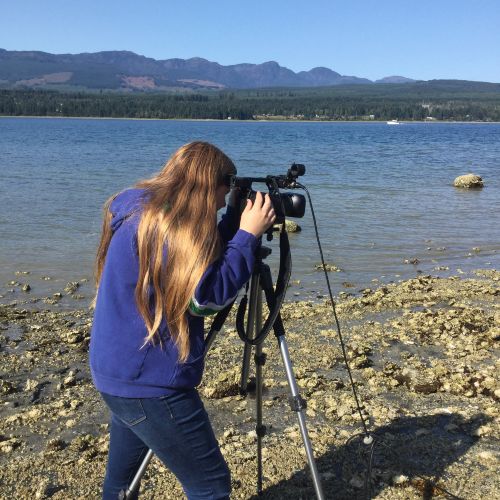 youth looking into camera on tripod on the beach